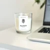 Krisha Essence Rose Petals soy jar candle sitting on a white desk next to a laptop, featuring a classic fresh cut roses candle fragrance.